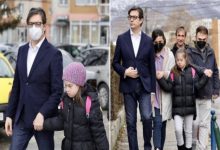 Yan yana iki kareden oluşan bir fotoğraf. Solda: Takım elbiseli bir adam, sokakta yürürken Down sendromlu küçük bir kızın elini tutuyor. Kız siyah montlu, pembe bere takıyor; okul yolunda gibi, yüzü ciddi. Adam koruyucu bir refleksle yanında. Sağda: Aynı kız bu kez ailesiyle birlikte yürüyor. Önde yine takım elbiseli adam, yanında yetişkinler ve arkalarında kız. Hepsi kalın montlu, sakin ama dikkatli adımlarla ilerliyor. Fotoğraf, bir çocuğun gündelik hayatında ailesinin desteğini ve birlikte yürüyüşünü sade, çarpıcı bir şekilde gösteriyor.