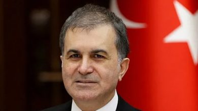 Kültür ve Turizm Bakanı Ömer Çelik'in bir fotoğrafı arkada Türk bayrağı görülmekte