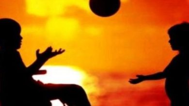 Görselde, biri tekerlekli sandalyede, diğeri ise ayakta duran iki çocuk karşılıklı olarak oyun oynuyor. Tekerlekli sandalyede oturan çocuğun elinde bir top tuttuğu görülüyor.