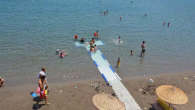 Engelli bireylerin denize girebilmesi için yapılmış özel bir platform ve denize giren insanlar fotoğrafta yer alıyor.
