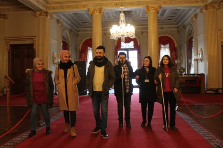 Rehber Özlem Yazgan saray içinde görme ve işitme engelli ziyaretçilerle geziyor.