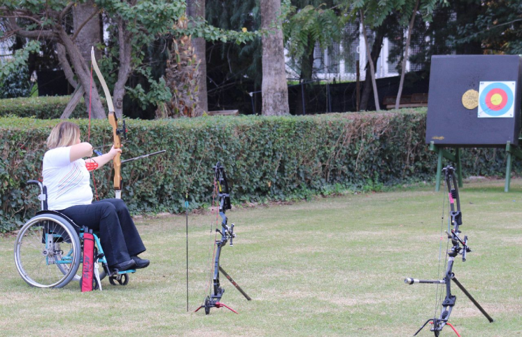 Kadın okçu Ebru Akköz sırtı dönük olarak antrenmanda ok atışı yaparken.