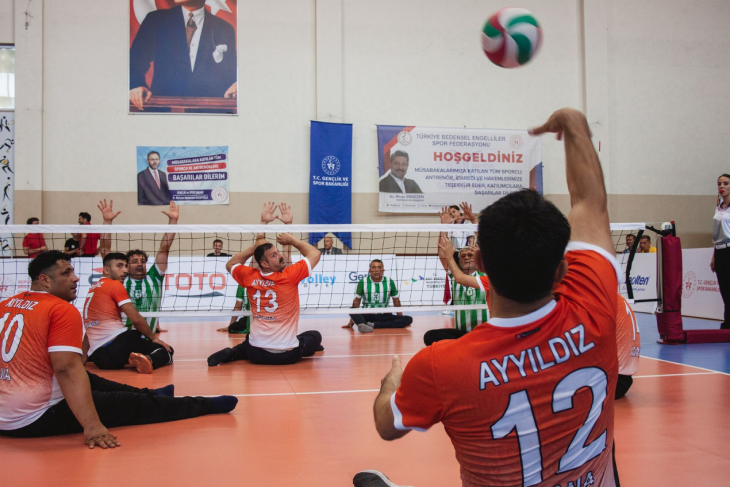 İki rakip takım oyuncuları oturarak voleybol maçı yapıyor.
