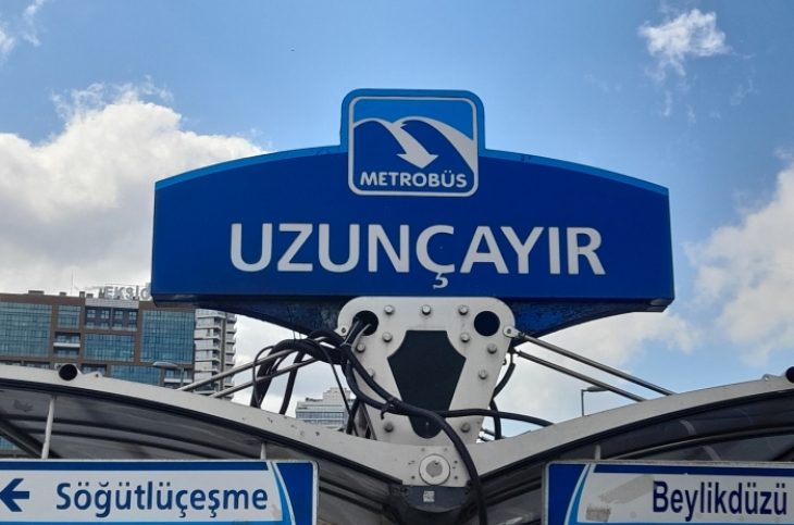 Büyük harflerle Uzunçayır yazılı Metrobüs tabelası altında Söğütlüçeşme ve Beylikdüzü yönlerini gösteren yön tabelaları.