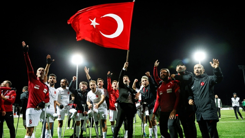 Türk bayrağı sallayan Teknik Direktör Osman Çakmak ve Ampute Futbol Milli Takımı sporcuları maç sonu seviniyor.