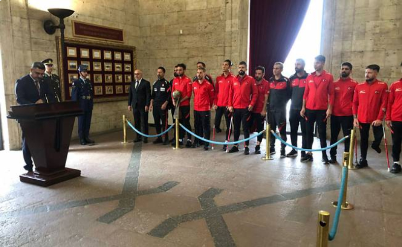 TBESF Başkanı Muaz Ergezen Anıtkabir hatıra defterine yazı yazarken, Ampute Futbol Milli Takımı sporcuları yan tarafta bekliyor.