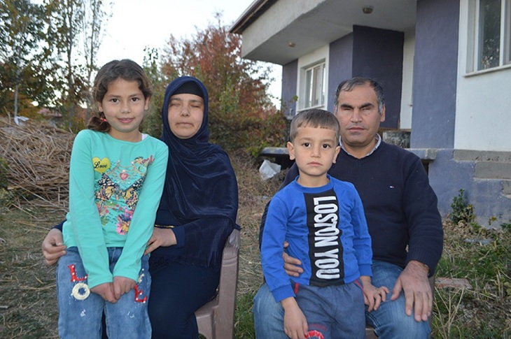 Görme engelli çift, kucaklarındaki 1 kız ve 1 erkek çocukları ile birlikte objektife yansıyor.