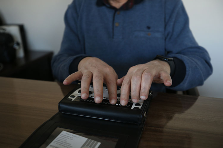Görme Engelli Avukat Salih Mehmet Aslan, parmakları ile braille klavye kullanarak yazı yazıyor.
