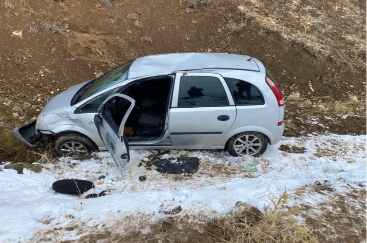 Kaza sonrası ön ve diğer bölümleri parçalanan otomobilin kar üstünde kapısı açık bulunuyor.