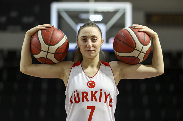İşitme Engelli Milli Basketbolcu Kübra Demir 7 numaralı forma giyerek, iki basketbol topunu omuzlarına alarak poz veriyor.