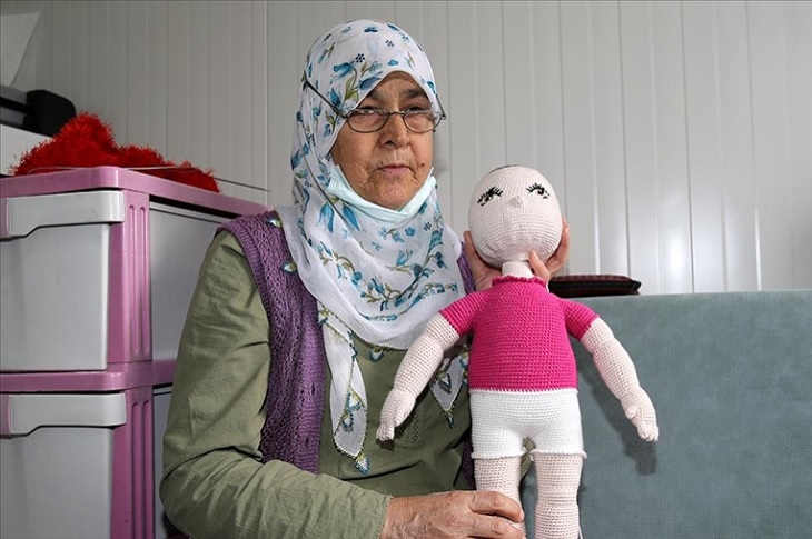 Kanser hastası kadın, tamamladığı örgü bebekle birlikte objektife yansıyor.