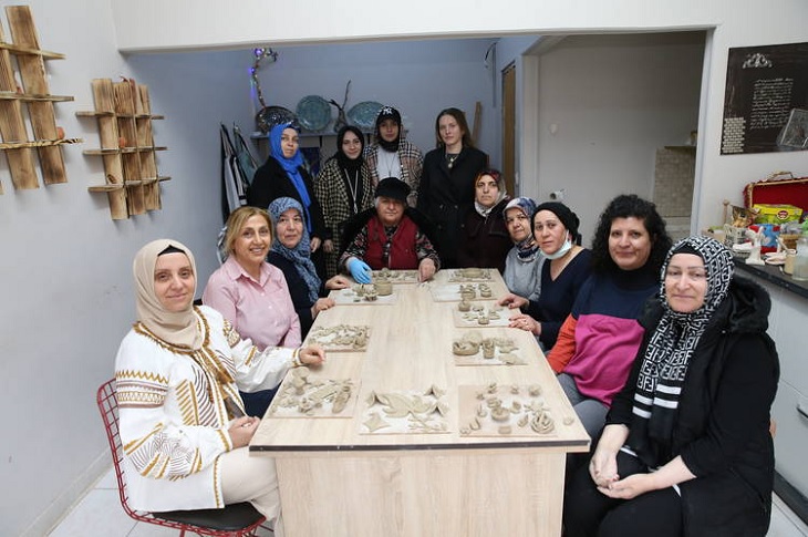 Etkinlikte bir araya gelen çok sayıda çok sayıda katılımcı, aynı masa etrafında bir arada objektife yansıyor.