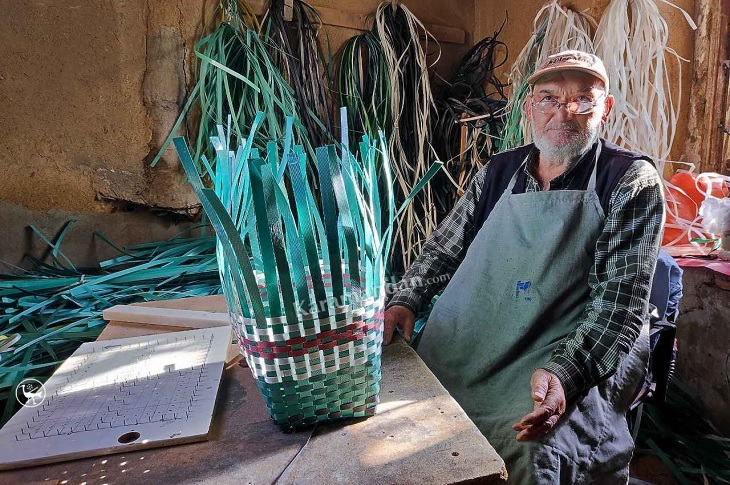 Yaşlı adam, örmeye devam ettiği plastik sepet ile birlikte objektife yansıyor.