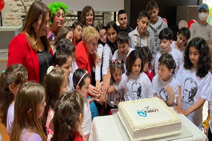 Masadaki dev pasta etrafında bir araya gelen çok sayıda özel çocuk objektife yansıyor.