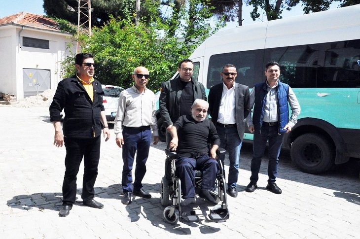 Sorumluluk sahibi 5 yetkili, akülü aracını teslim alan engelli bireyle birlikte objektife yansıyor.