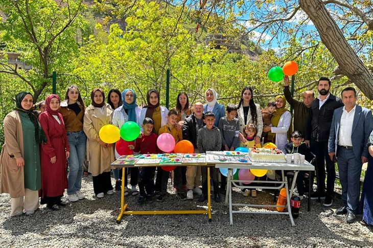Masa üzerindeki oyuncaklar ve yaş pasta ile birlikte çekilen toplu hatıra resmi objektife yansıyor.