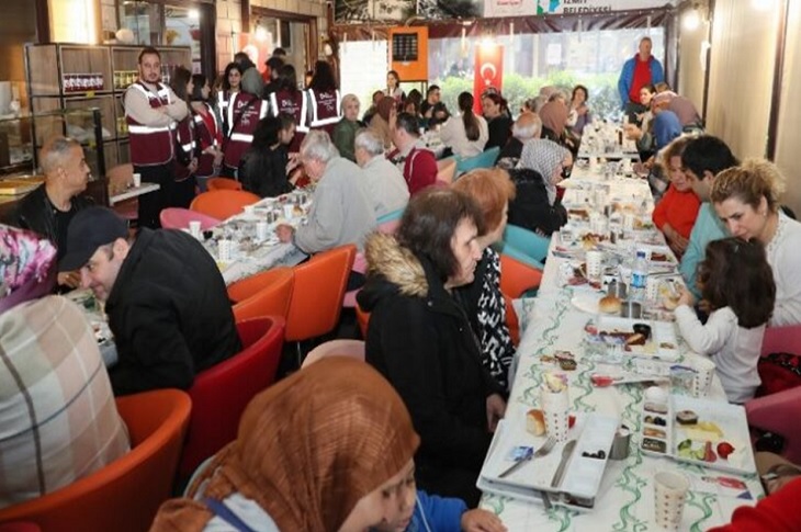 Aynı yemek masalarında bir araya gelen çok sayıda engelli ve yakını objektife yansıyor.