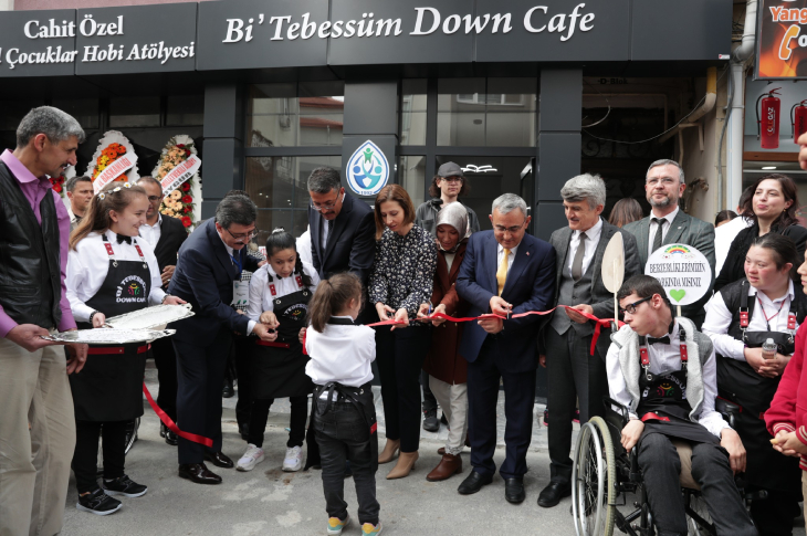 Kütahya Valisi Ali Çelik, katılımcılar ile down sendromlu gençler Down Cafe'nin açılış kurdelesini kesiyor.