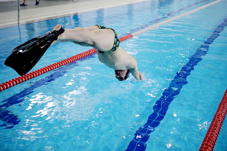 Başarılı sporcunun havuza balıklama atladığı ana dair bir görüntü objektife yansıyor.