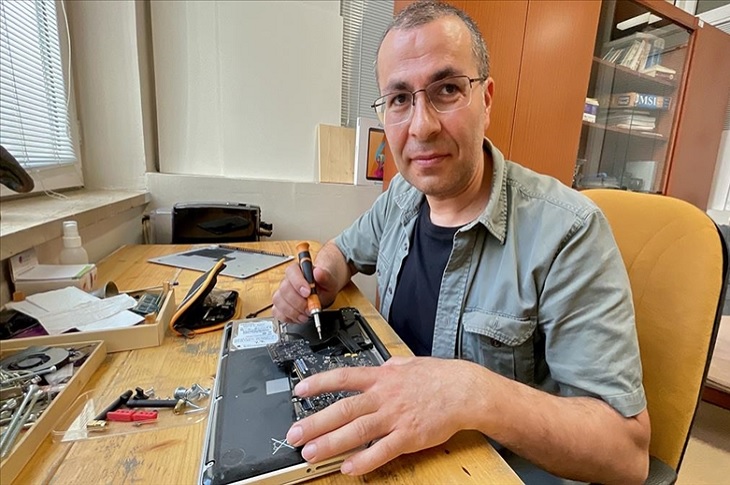 Elektronik aletin tamirini yapan bir birey objektife yansıyor.