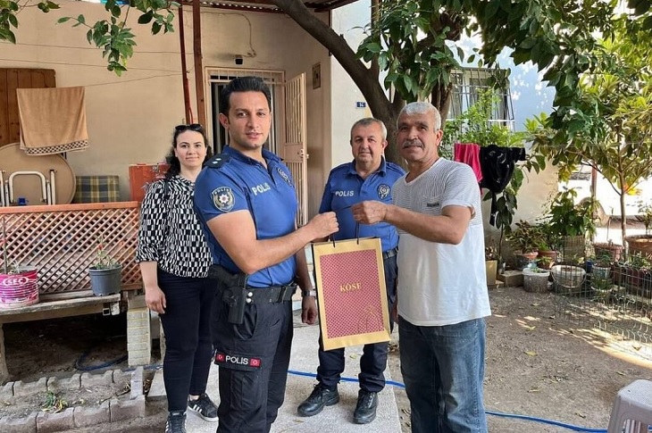 İki polis memuru tarafından ziyaret edilen ev sakinlerine hediyelerinin teslim edildiği ana dair bir görüntü objektife yansıyor.