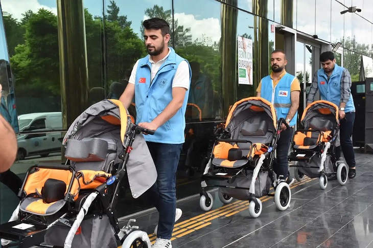 3 görevli memur, taşıdığı akülü araçla birlikte objektife yansıyor.