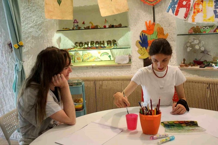 İlgili öğretmen, aynı masada öğrencisi Dicle Sultan Altun'un resim yapımını seyrediyor.