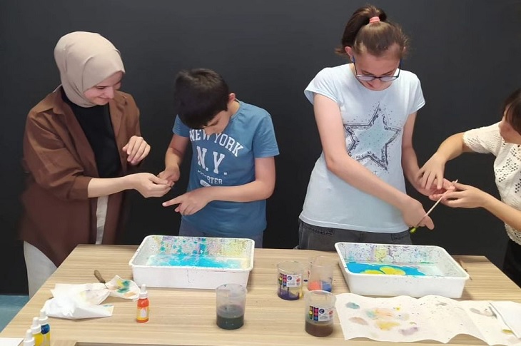 Masada ebru sanatı yapan iki öğrenciye hocaları birebir destek veriyor.