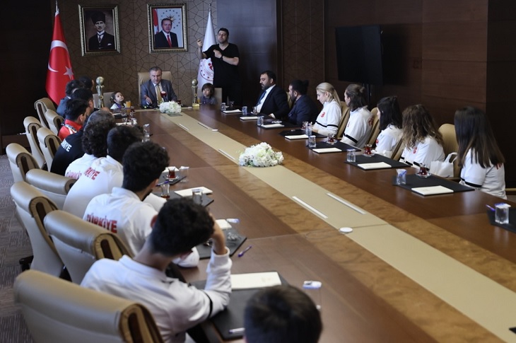 Aynı masa etrafında oturan sporcuların Bakan'ın konuşmasını dinlediği ana dair bir görüntü objektife yansıyor.