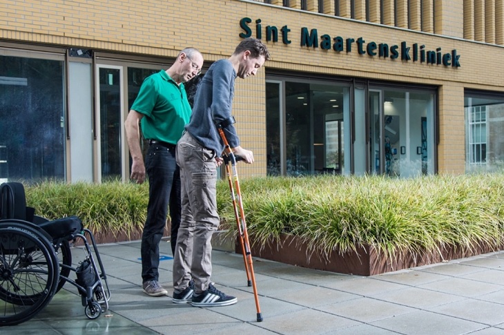 Elbise sayesinde değnekleriyle tekerlekli sandalyesinden kalkıp yürüyen birey objektife yansıyor.