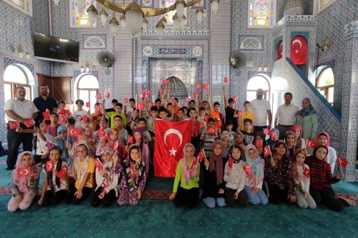 Cami içinde Türk bayrağı açan kursiyer öğrencilerin toplu hatıra resmi objektife yansıyor.