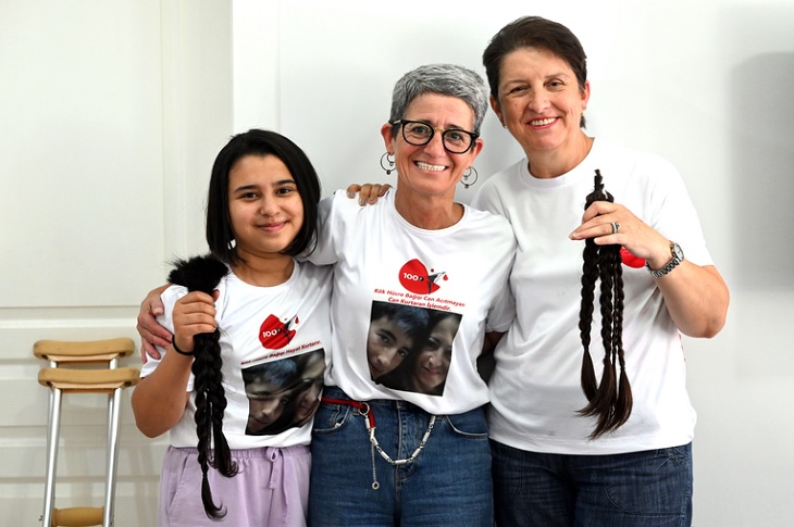 Seher Karakuş ve Şadiye Kılıç ellerinde bağışlamak üzere kestirdikleri saçlarıyla birlikte objektife yansıyor.