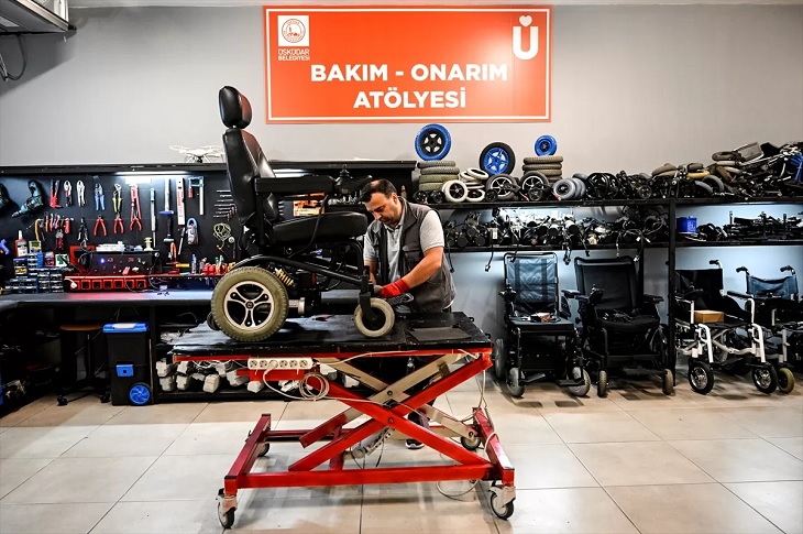 Bakım-Onarım Atölyesinde bir tamircinin akülü aracı tamir ettiği ana dair görüntü objektife yansıyor.