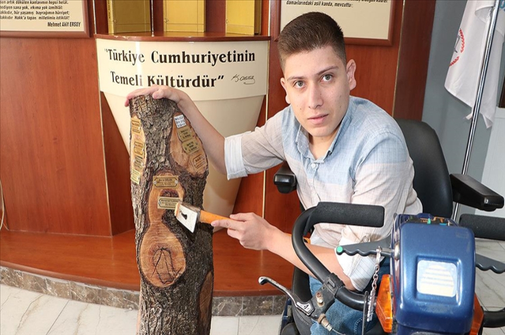 Öğrenci Mehmet Akif Yıldırımer tekerlekli sandalyede oturarak yaş kütüğe birincilik paketini çakıyor.