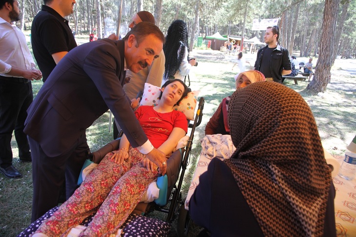 Dernek Başkanı Hilmi Yaman'ın ağır engelli bireyin yakınlarıyla sohbet ettiği ana dair bir görüntü objektife yansıyor.