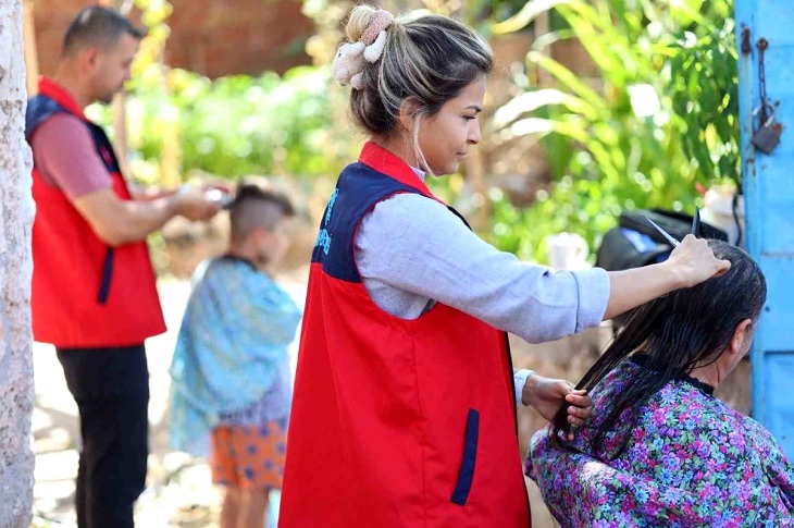 Açık havada, saç bakımları yapılan ihtiyaç sahipleri objektife yansıyor.
