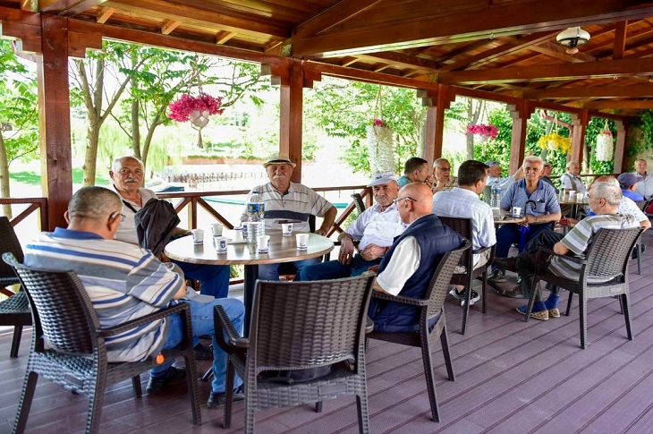 Lokaldaki masalarda oturan çok sayıda yaşlı birey objektife yansıyor.