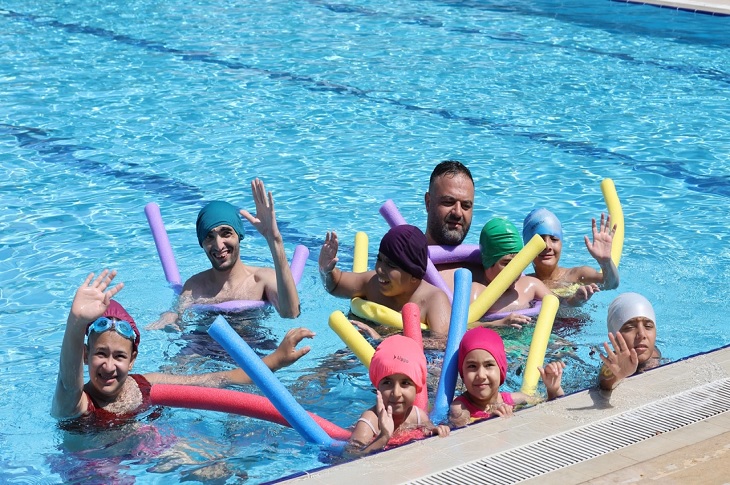 Havuzda bir arada yüzen çok sayıda özel gereksinimli çocuk objektife yansıyor.