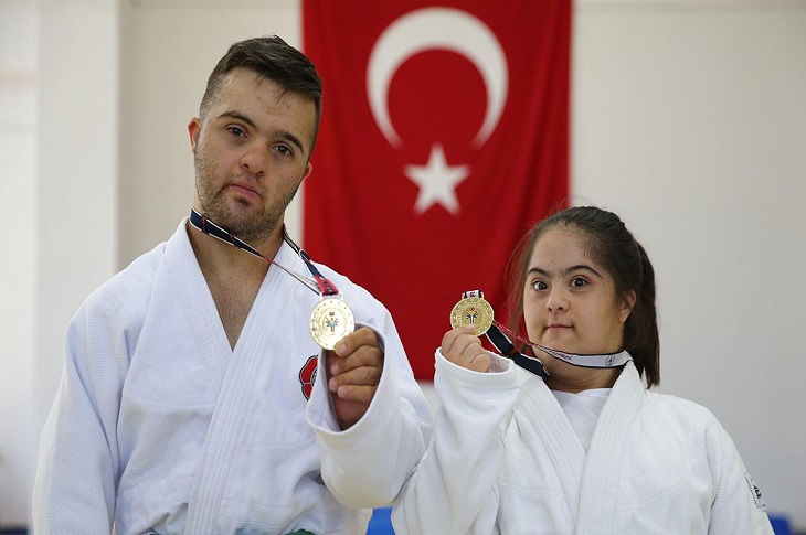 Down sendromlu iki başarılı judocu, madalyaları ile birlikte objektife yansıyor.
