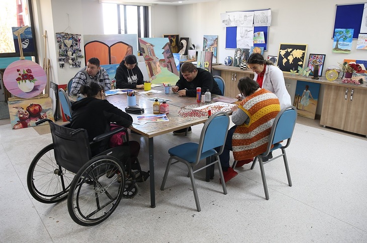 Aynı masa etrafında resim çalışmaları yapan engelli bireyler objektife yansıyor.