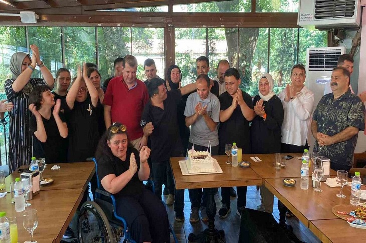 Katılımcıların pasta üflemesi sonrası alkışladığı ana dair bir görüntü objektife yansıyor.