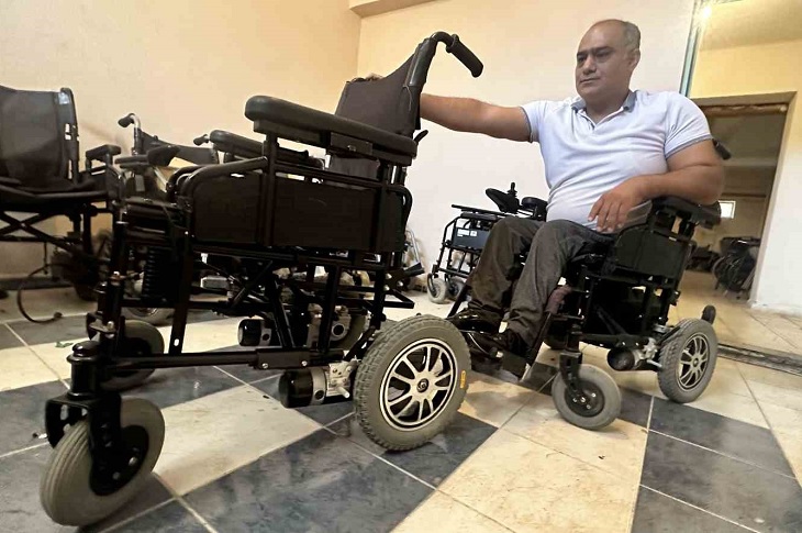 Akülü aracında, akülü aracı tamir eden Metin Fırat objektife yansıyor.