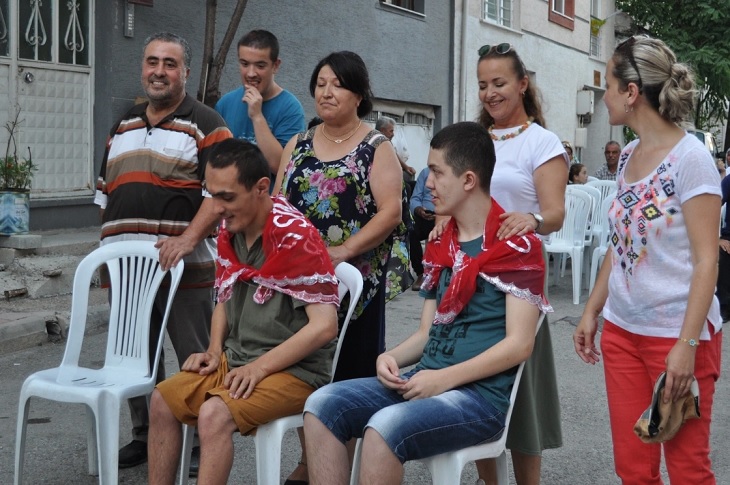 Düzenlenen asker eğlencesinde, sandalyede oturan iki genç yakınlarıyla birlikte objektife yansıyor.