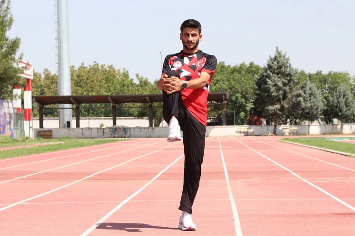 Koşu pistinde ısınma hareketleri yapan Mikail Al objektife yansıyor.