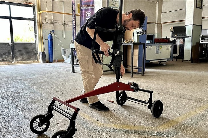 Metal Teknolojileri öğretmeni Tuğrul Akdemir, atölyede yapımını tamamladığı yürüteçle birlikte objektife yansıyor.