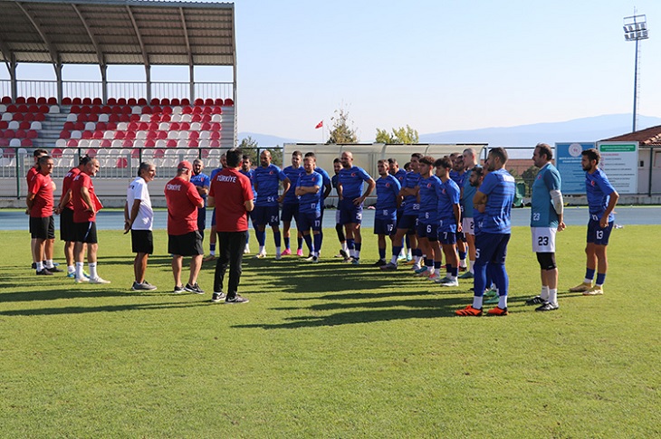 Yeşil sahada, antrenman arası ayak üstü yapılan bir mini toplantı görüntüsü objektife yansıyor.
