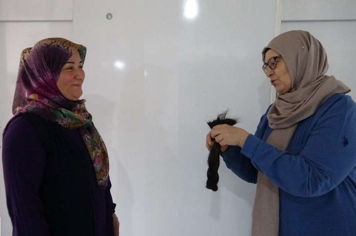 Kesilen saçını bağışlayan Fatma Üresin ve saçı devralan Cemaliye Bardakçı objektife yansıyor.
