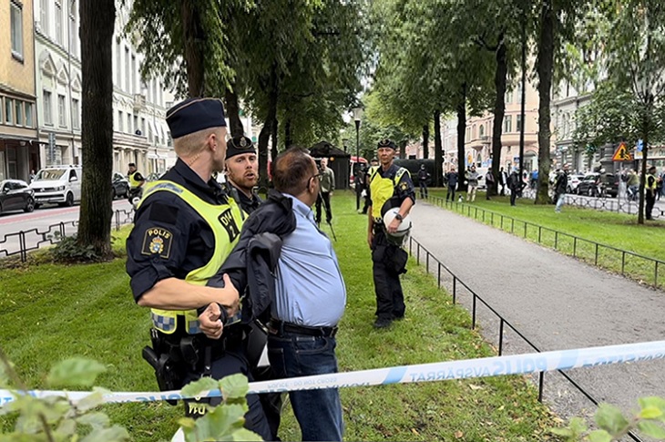 Kur'an yakıldığı sırada, Pakistanlı Malik'in iki İsveç polisi tarafından sıkıca tutulduğu ana dair bir görüntü objektife yansıyor.