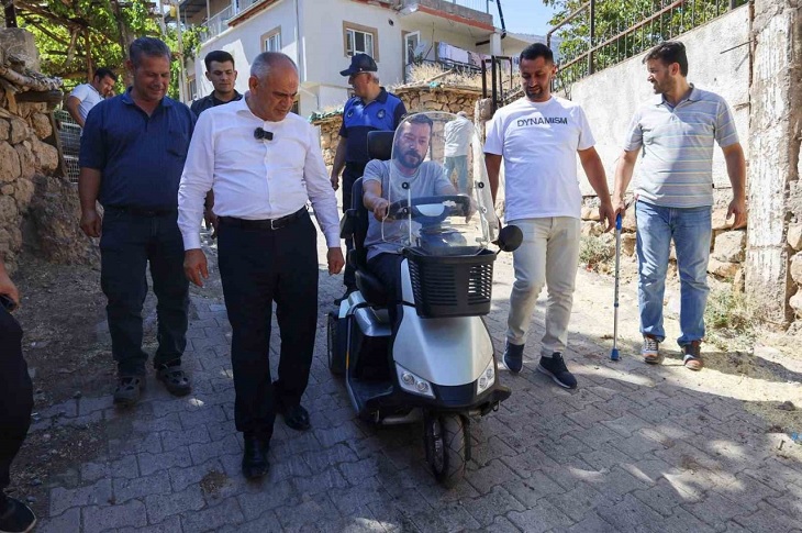 Motorlu aracını ilk kez deneyen Mehmet Küçük, yetkililerle birlikte objektife yansıyor.