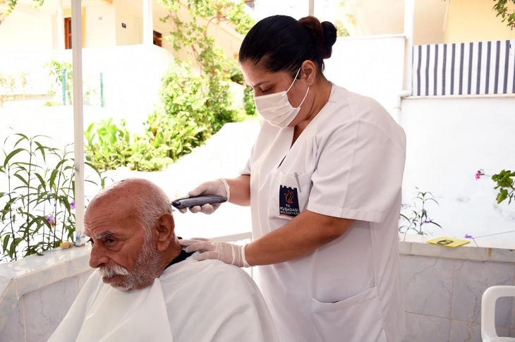 Saç tıraşı olan bir yaşlı birey objektife yansıyor.